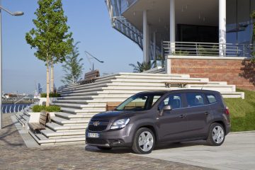 Vista lateral del Chevrolet Orlando aparcado frente a un edificio moderno.