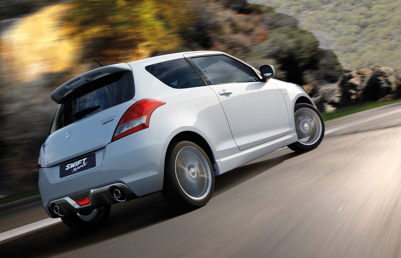 Vista dinámica de la trasera y lateral del Suzuki Swift Sport en acción.