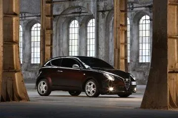 Alfa Romeo MiTo exhibido con elegancia en un entorno industrial.