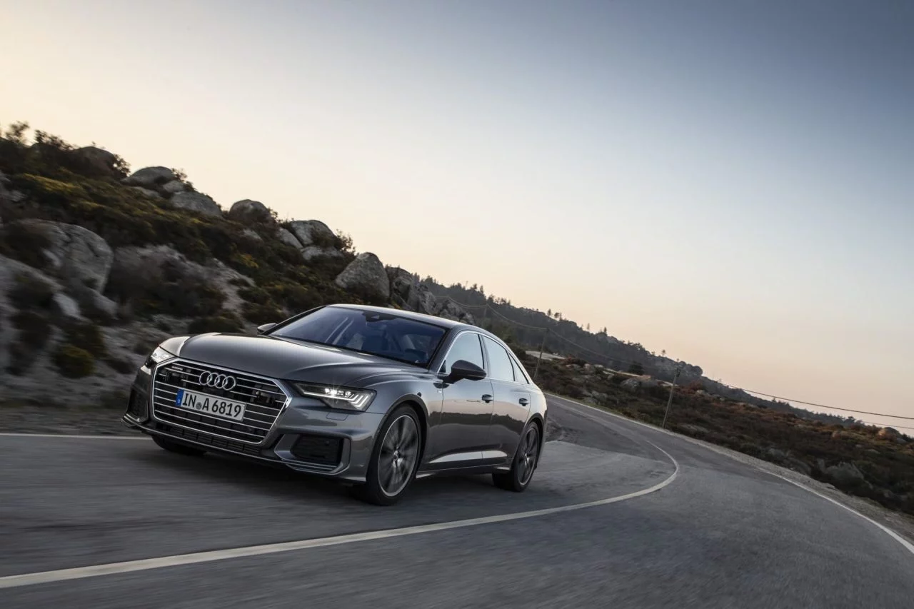 Vista lateral del Audi A6 en movimiento sobre carretera de montaña