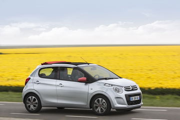 Vista lateral del Citroën C1 rodando junto a un campo amarillo.