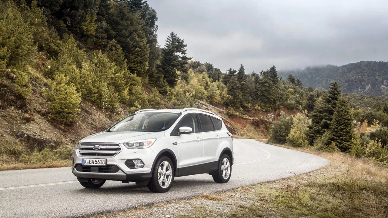 Vista dinámica del Ford Kuga en carretera, mostrando su diseño frontal y lateral.