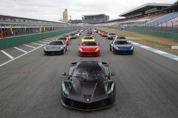 Vista frontal del Ferrari LaFerrari liderando un conjunto de superdeportivos en la pista.