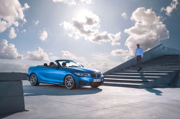 BMW Serie 2 Cabrio estacionado, techo rebatido y cielo despejado de fondo.