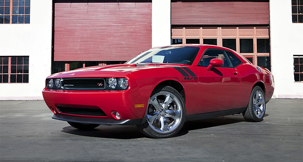 Vista lateral de Dodge Challenger en rojo, mostrando su perfil musculoso y deportivo.