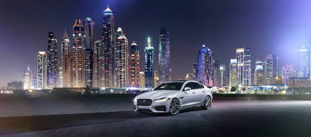 Vista frontal y lateral del Jaguar XF con un impresionante fondo urbano nocturno