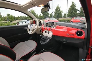 Vista lateral del salpicadero y asientos del Fiat 500 en tonos rojos y blancos.