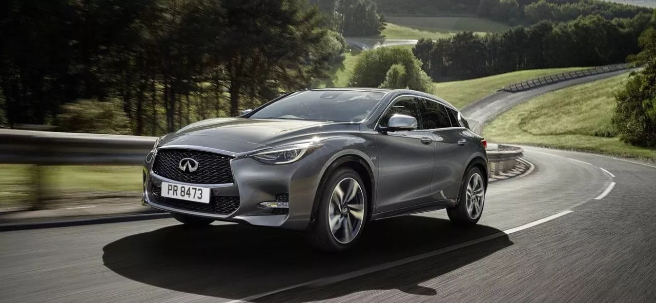 Vista dinámica del Infiniti Q30 en carretera, destacando su diseño frontal y lateral.