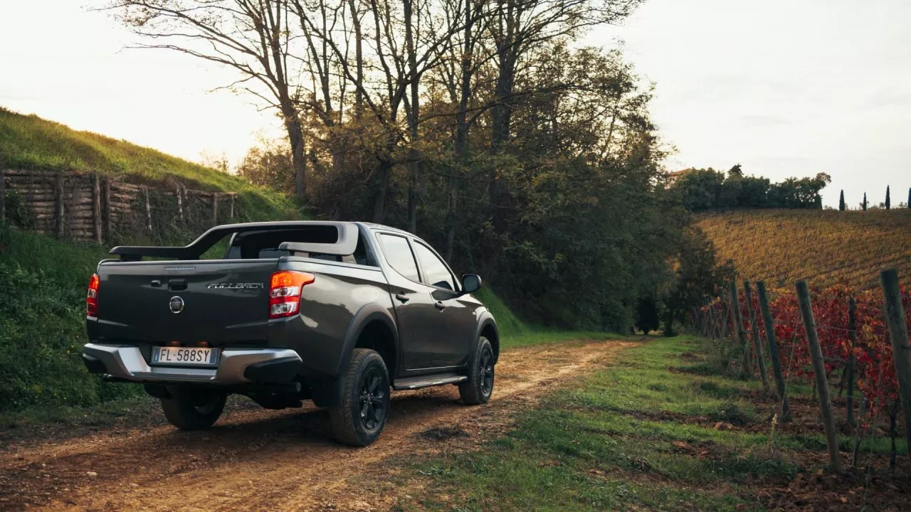 Vista lateral del Fiat Fullback en un entorno campestre, resaltando su perfil robusto.