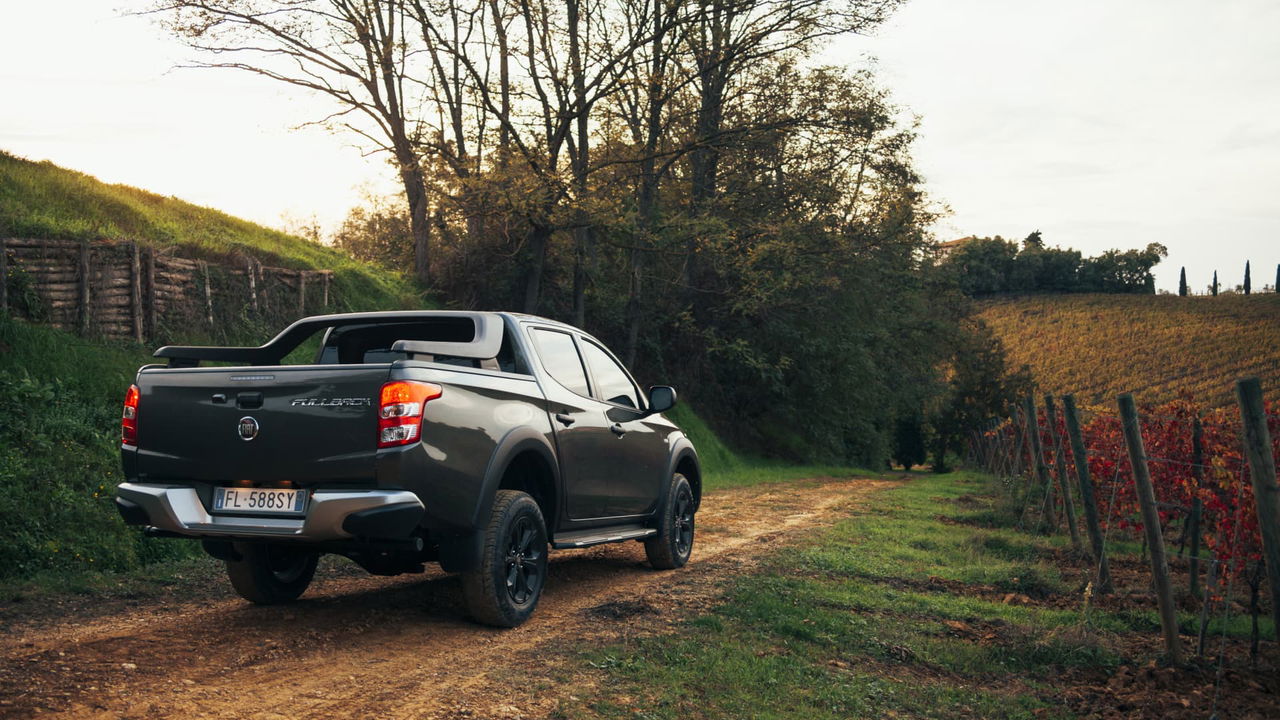 Vista lateral del Fiat Fullback en un entorno campestre, resaltando su perfil robusto.