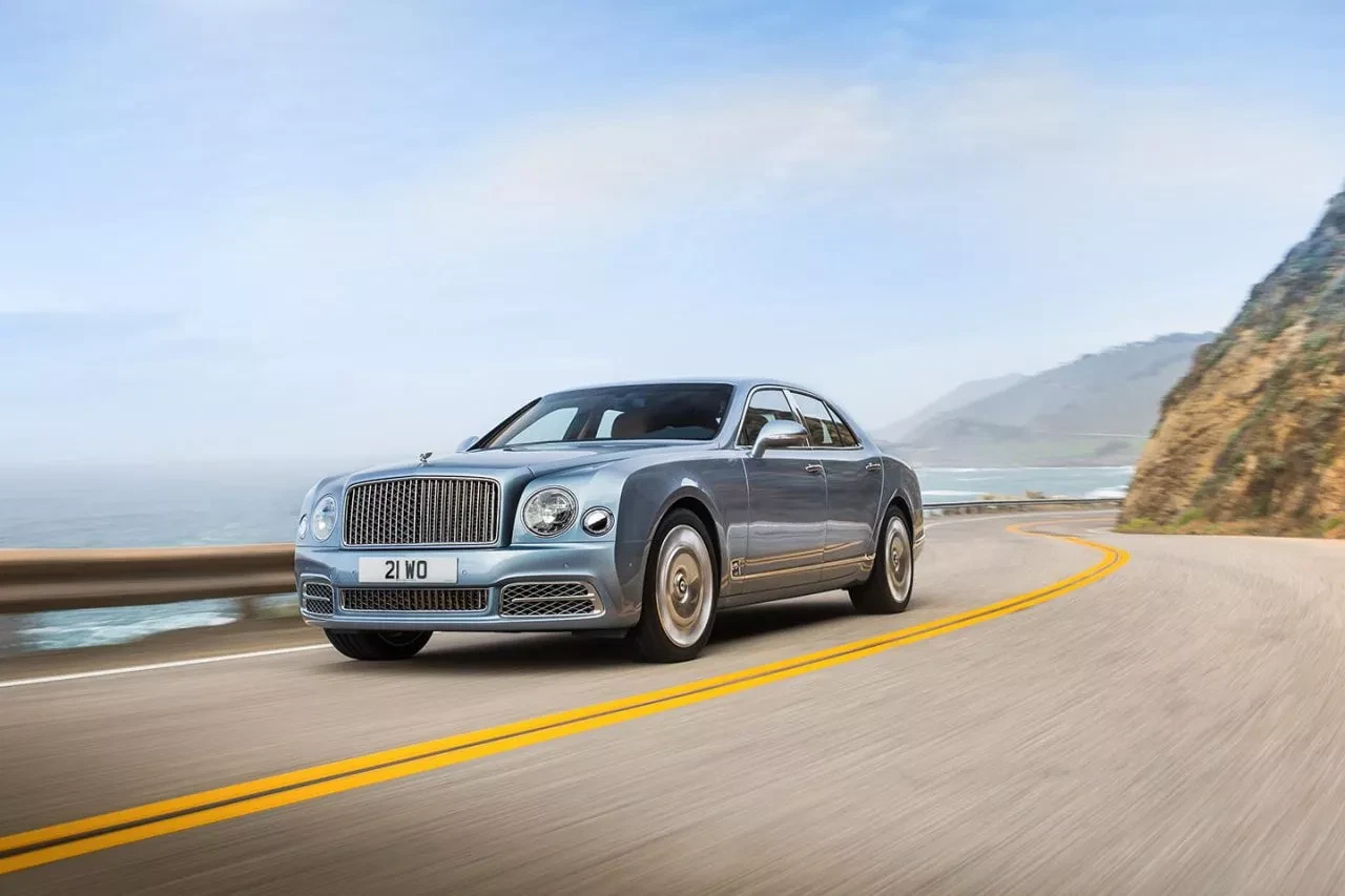 Vista lateral del Bentley Mulsanne en una carretera costera, mostrando su elegante silueta.