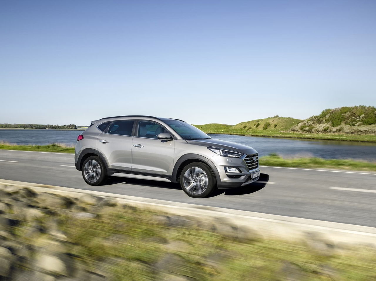 Vista lateral del Hyundai Tucson en movimiento mostrando su línea dinámica