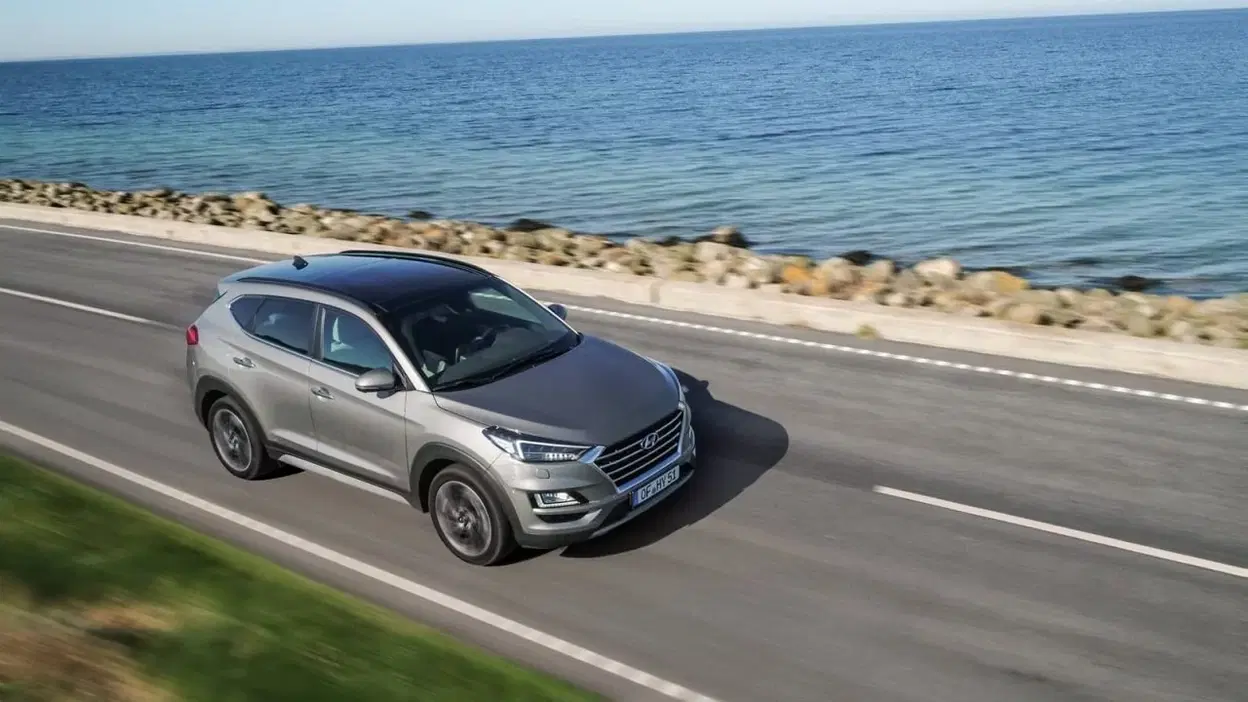 Vista lateral del Hyundai Tucson rodando junto al mar, destacando su diseño aerodinámico.