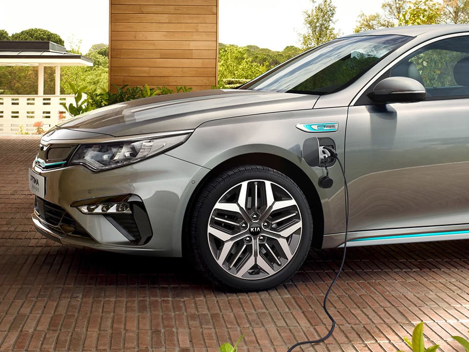 Vanguardista Kia Optima PHEV cargando, diseño elegante resaltado por su linaje lateral.