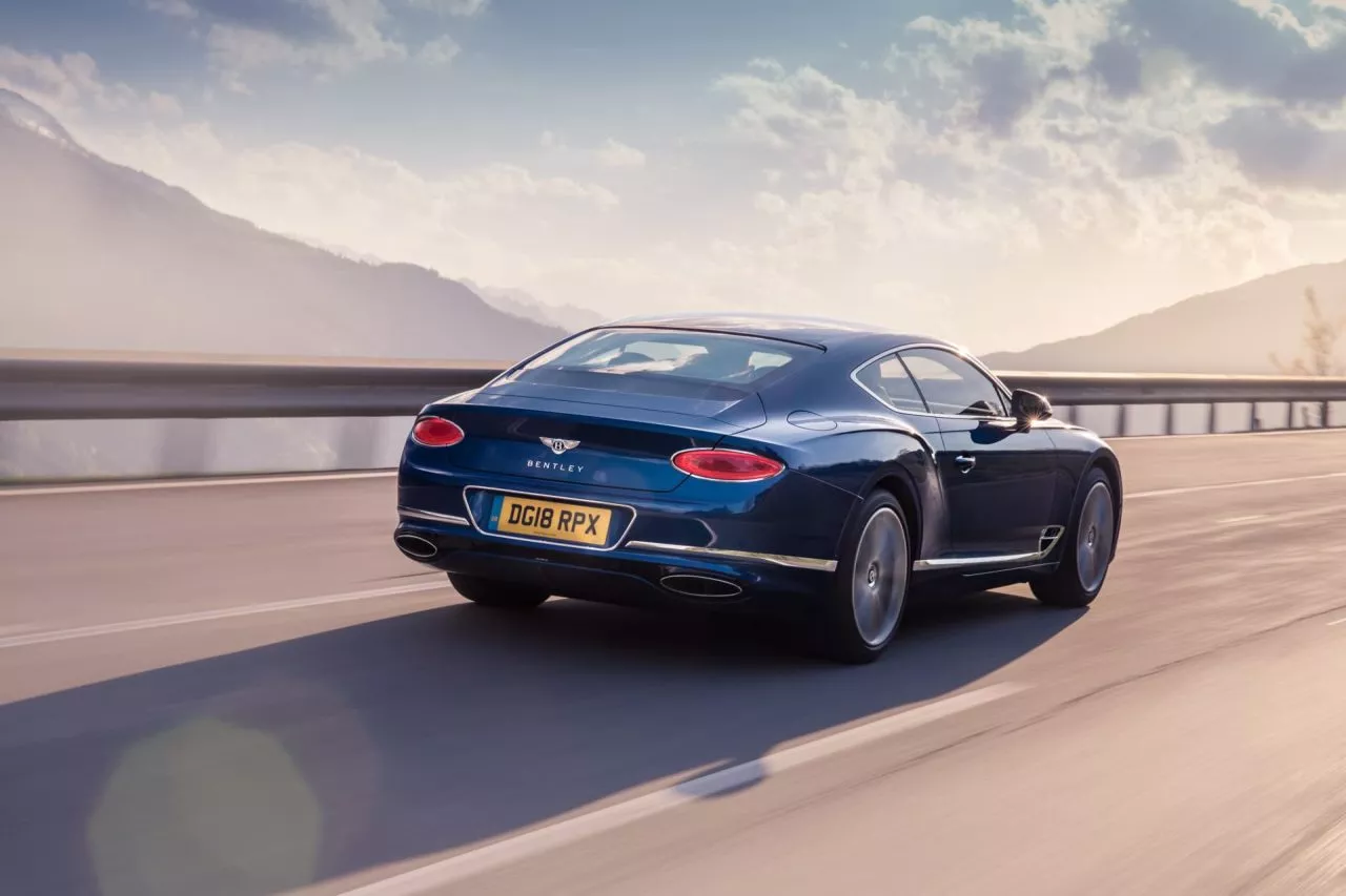 Vista dinámica de un Bentley Continental GT en carretera, destacando su línea trasera.