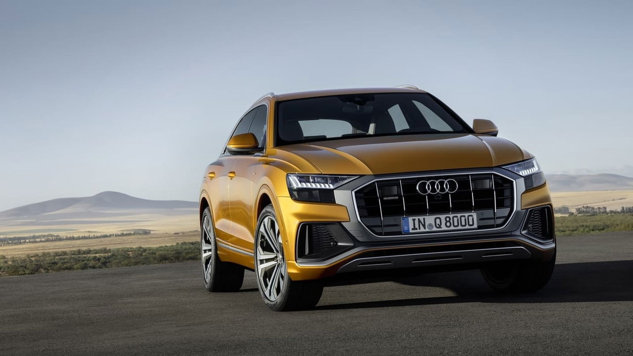 Vista dinámica del Audi Q8 en una carretera abierta, resaltando su diseño frontal.