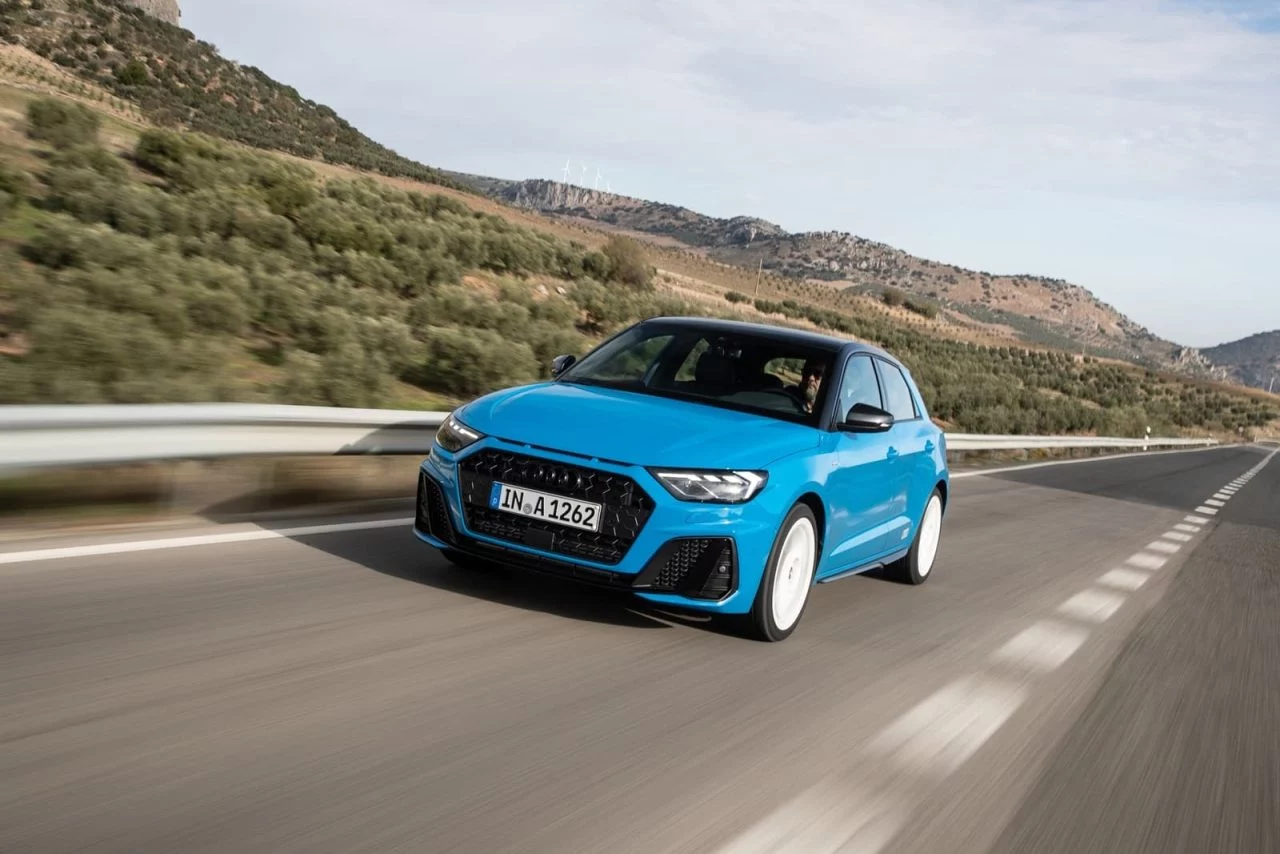 Vista dinámica del Audi A1 en carretera, destacando su frontal y línea lateral.