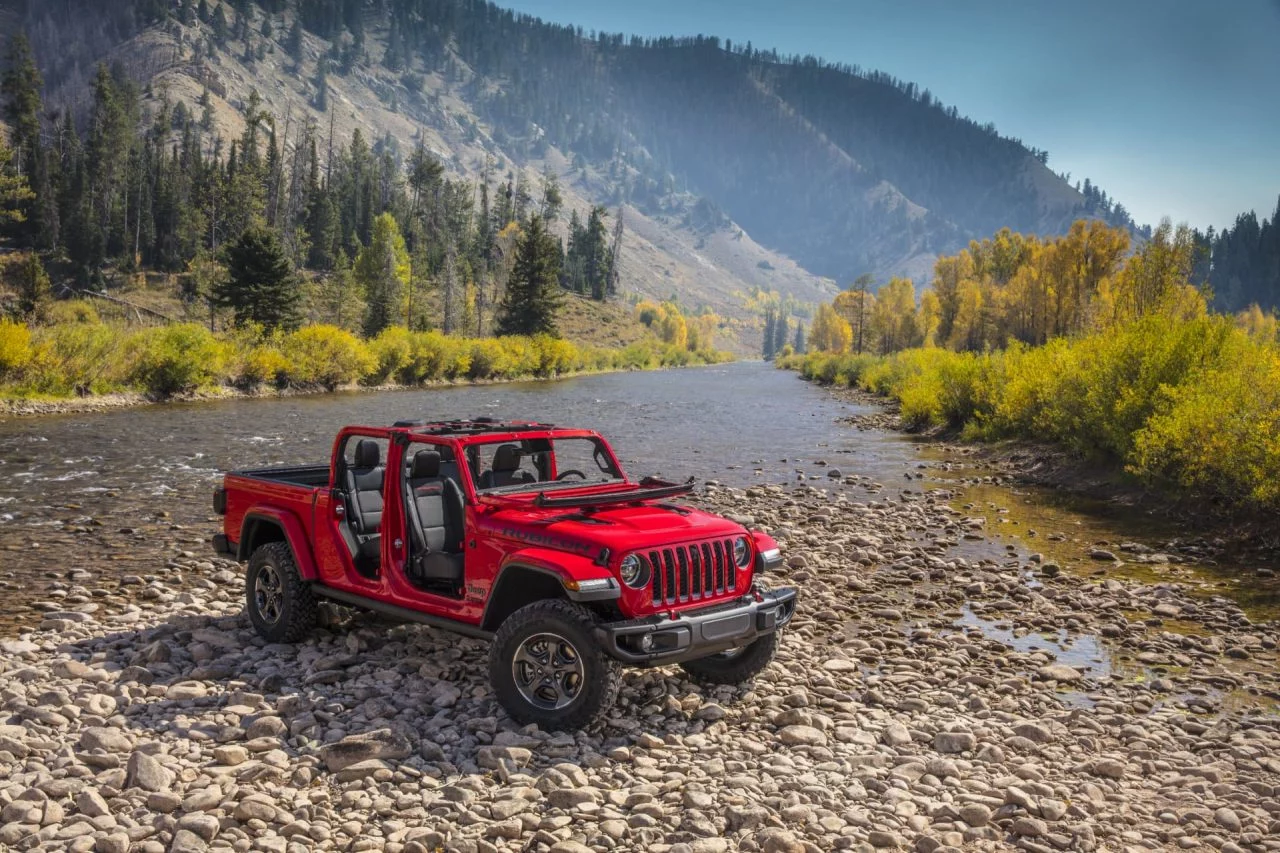 Jeep Gladiator superando terreno rocoso cerca de un río, resaltando su capacidad todoterreno.