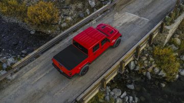 Vista aérea de un Jeep Gladiator rojo circulando por una vía elevada.