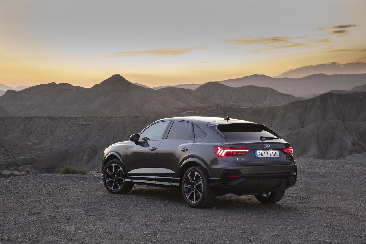 Vista trasera y lateral del Audi Q3 Sportback, iluminación crepuscular, resalta su diseño deportivo.