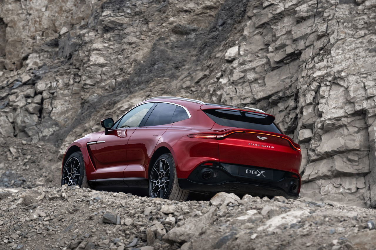 Vista lateral de un Aston Martin DBX en rojo, destacando su línea deportiva.