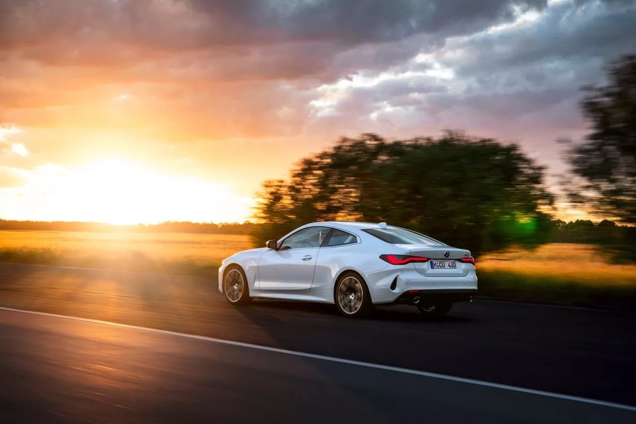 BMW Serie 4 captado en movimiento al atardecer, destacando su diseño lateral.