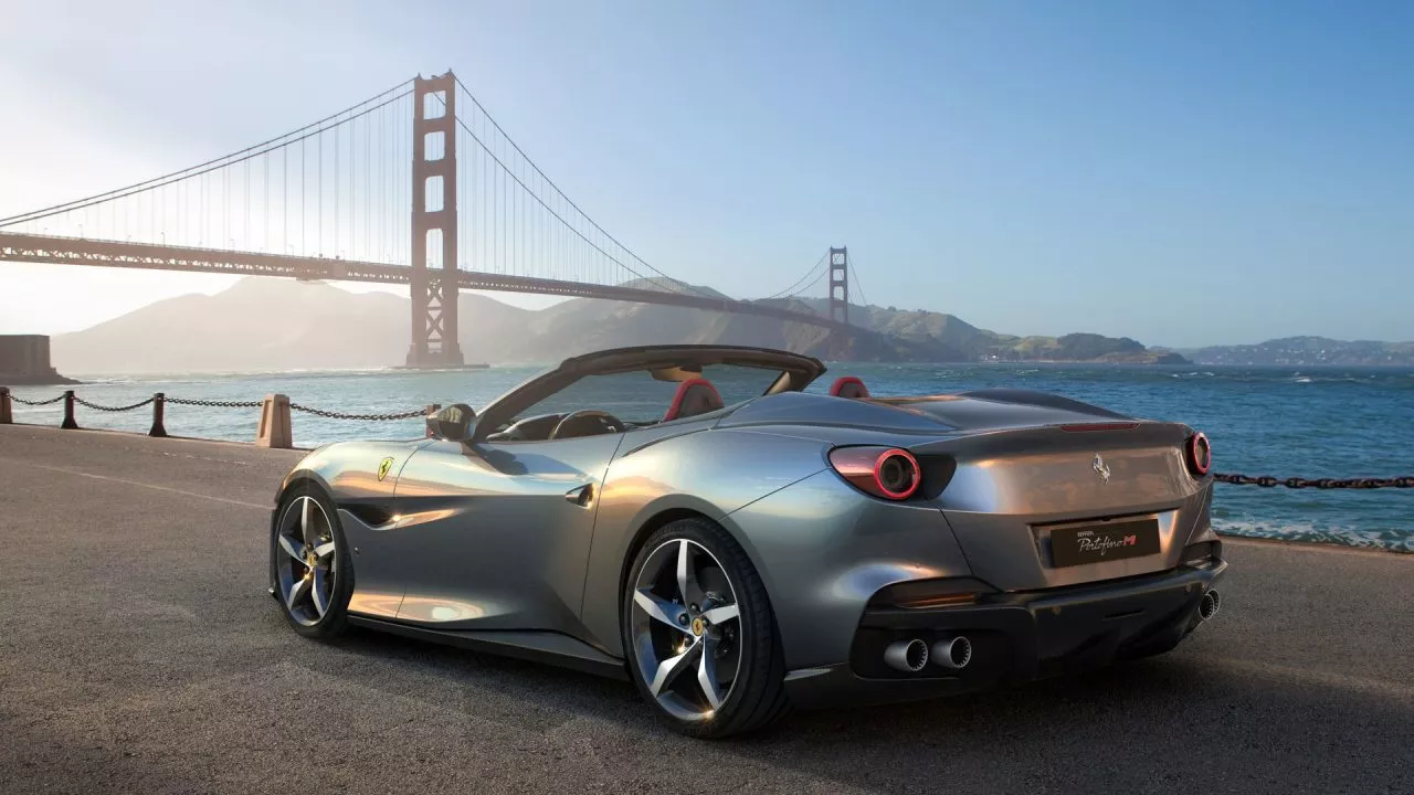 Vista lateral del Ferrari Portofino M con un puente en el fondo