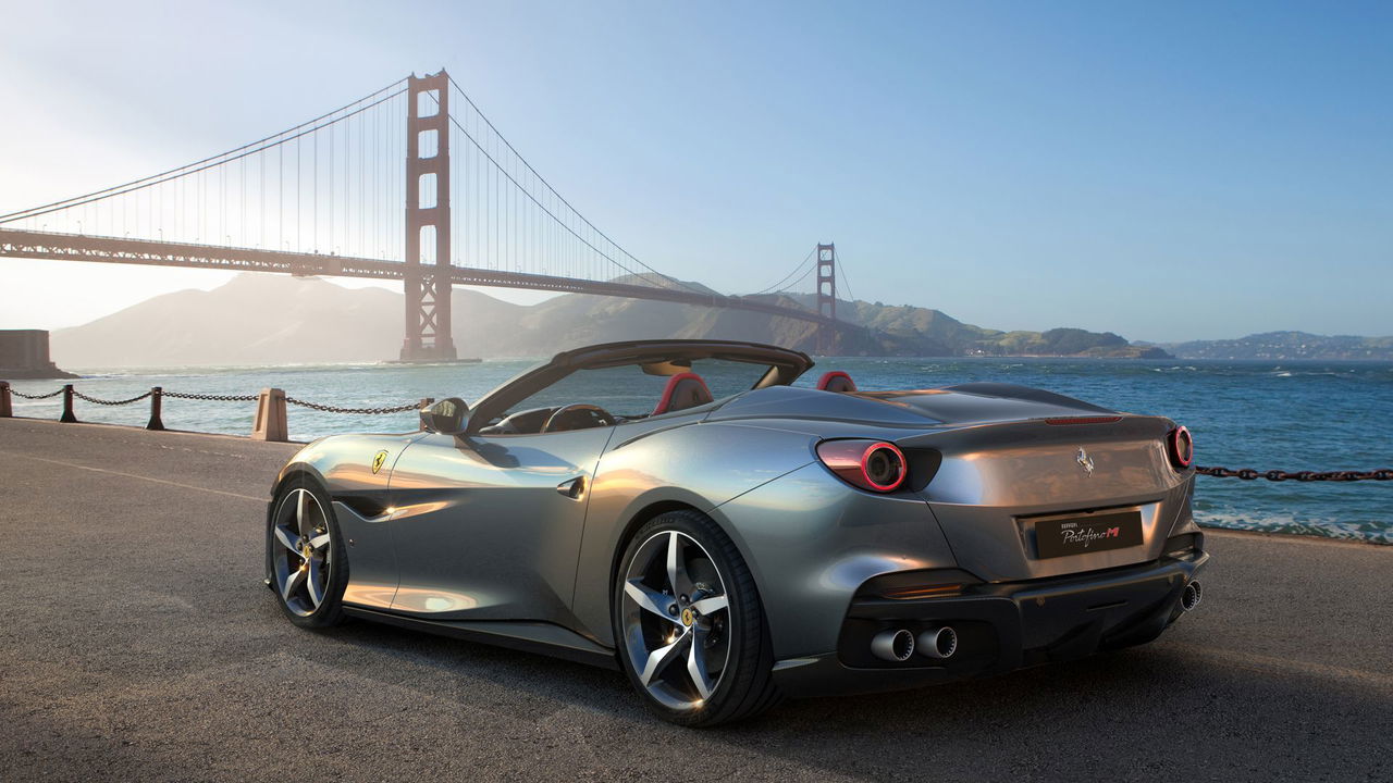 Vista lateral del Ferrari Portofino M con un puente en el fondo