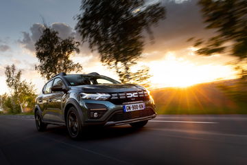 Vista dinámica del Dacia Sandero con el nuevo logo en plena ruta al atardecer