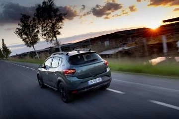 Vista dinámica del Dacia Sandero en movimiento, mostrando líneas traseras y perfil lateral.