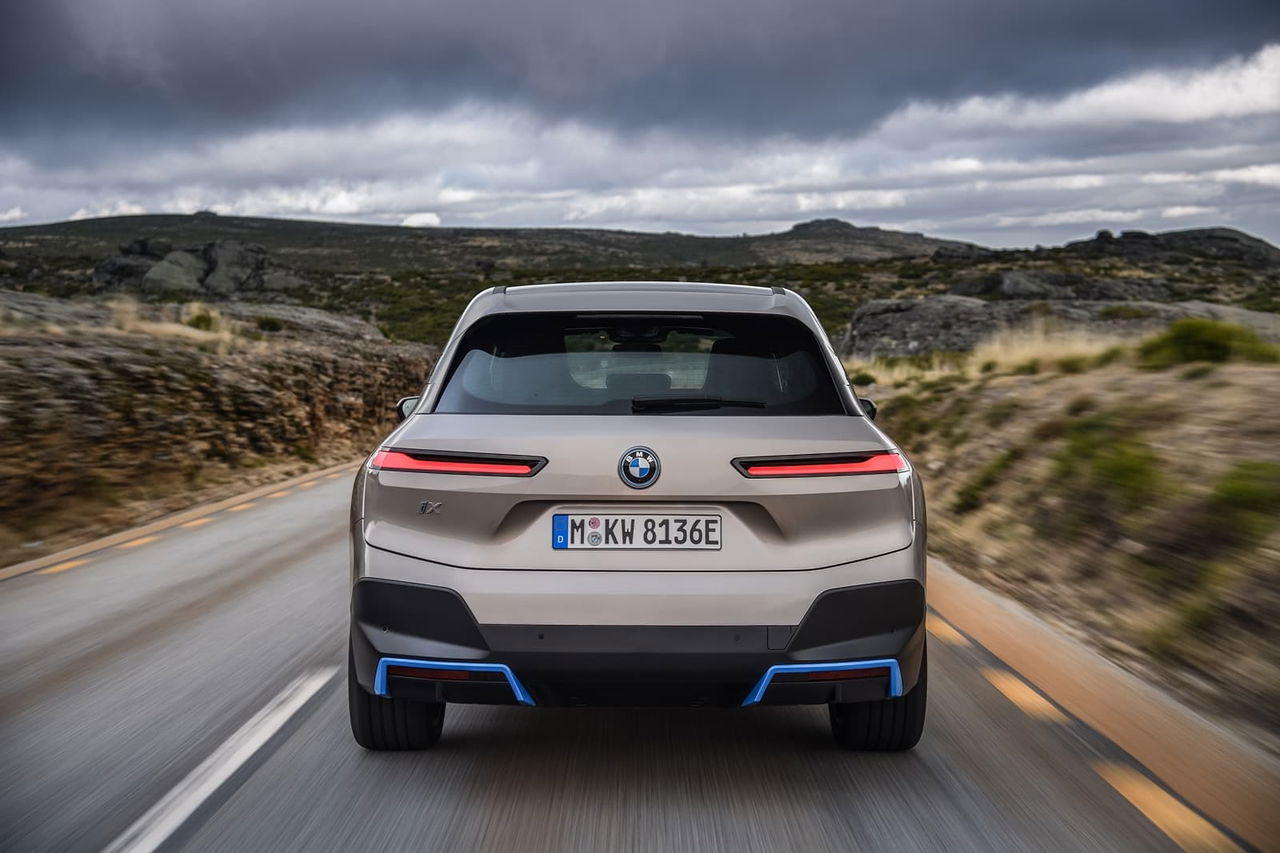 Vista trasera del BMW iX en movimiento, destacando su diseño y faros LED.