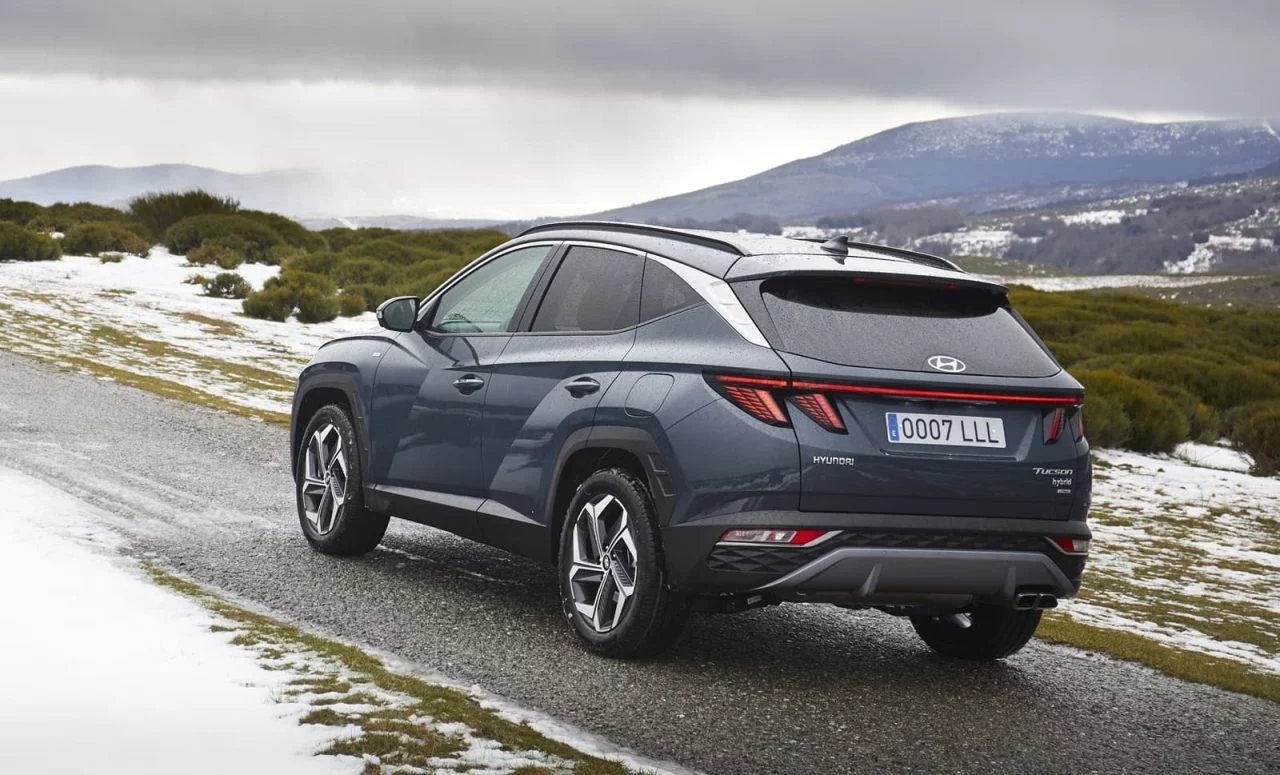 Vista trasera y lateral del Hyundai Tucson en carretera abierta, mostrando su diseño robusto y aerodinámico.