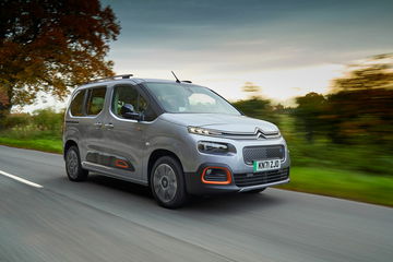 Vista dinámica del Citroën Berlingo circulando por una vía arbolada.