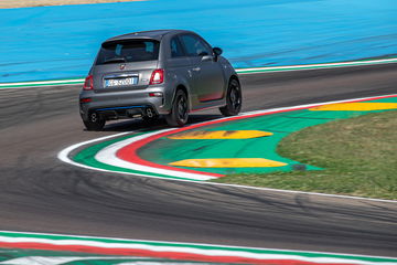 Abarth 595 en plena acción sobre la pista, mostrando su lado trasero y lateral.