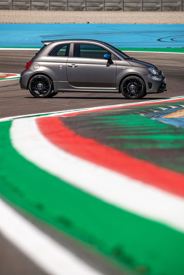 Vista lateral del Abarth 595 en pista, mostrando sus líneas deportivas.