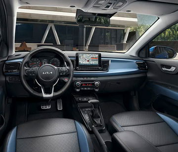 Cabina moderna del Kia Rio con volante multifuncional y sistema de infoentretenimiento.