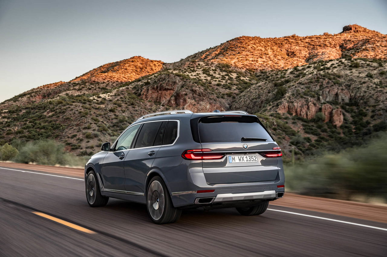 Vista dinámica del BMW X7 en carretera, mostrando su elegante diseño trasero y lateral.