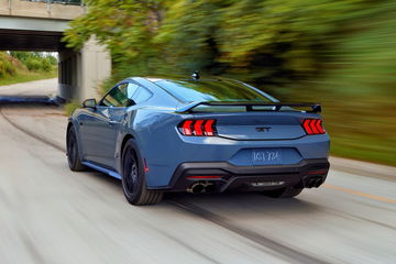 Captura dinámica del Ford Mustang mostrando su musculosa silueta y pilotos traseros icónicos.