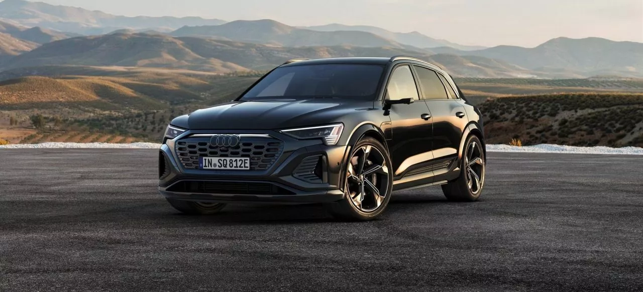 Vista dinámica del Audi Q8 e-tron mostrando su frontal y perfil lateral.