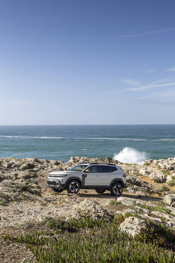 Vista lateral del Dacia Duster sobre rocas frente al mar.