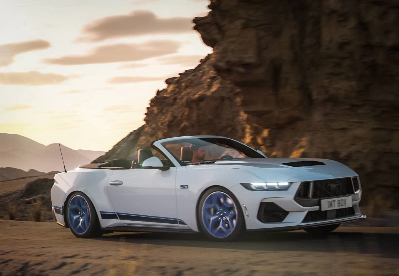 Vista lateral del Ford Mustang California Special 2024 rodando en carretera con atardecer de fondo.