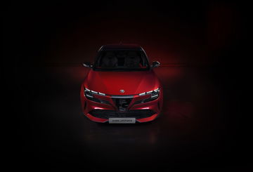 Vista frontal del Alfa Romeo con iluminación que acentúa su diseño agresivo.