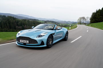 Vista dinámica del Aston Martin DB12 Volante en carretera, destacando su diseño y aerodinámica.