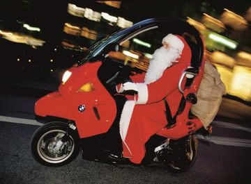 Vista dinámica de BMW C1 en movimiento con conductor vestido de Santa Claus.