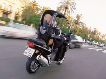 Vista dinámica del BMW C1 en circulación, mostrando su diseño lateral único.