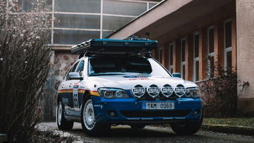 Vista frontal y lateral de un BMW Serie 7 preparado para rally, con barras de luces y portaequipajes.