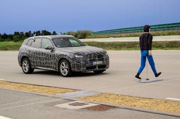 BMW X3 en fase de pruebas con camuflaje típico, vista lateral en movimiento.