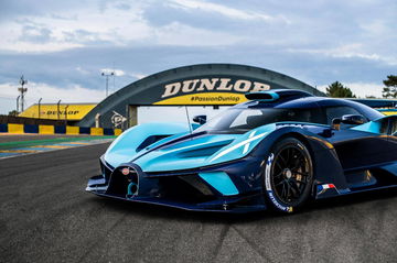 Bugatti azul recortando curva con neumáticos Dunlop, presencia imponente.