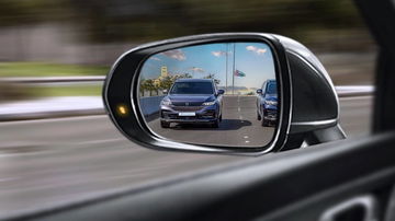 Reflejo de un vehículo en movimiento captado desde el espejo retrovisor.