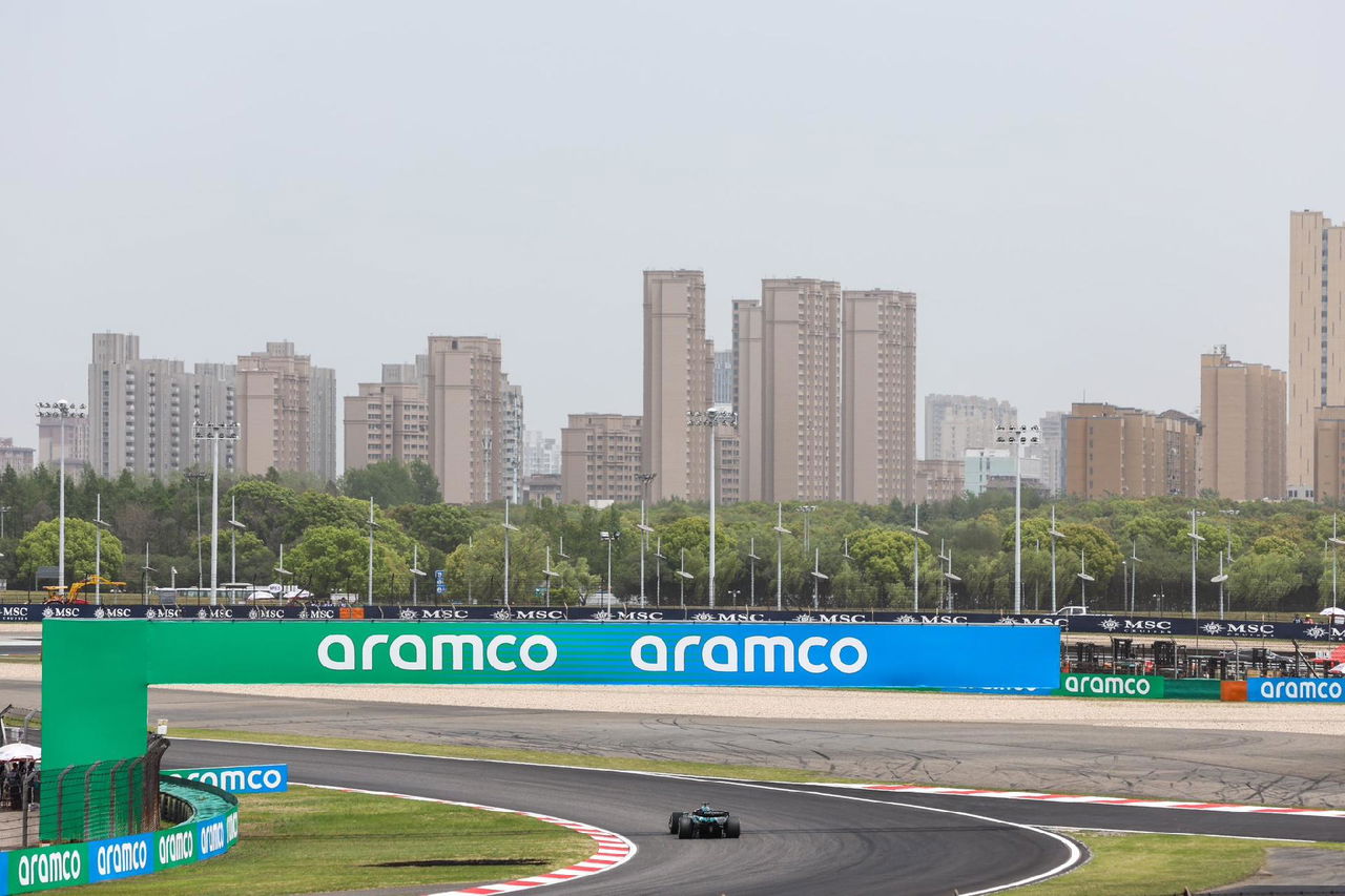 Vista lateral del circuito con el coche de F1 en la distancia bajo un cielo nublado.